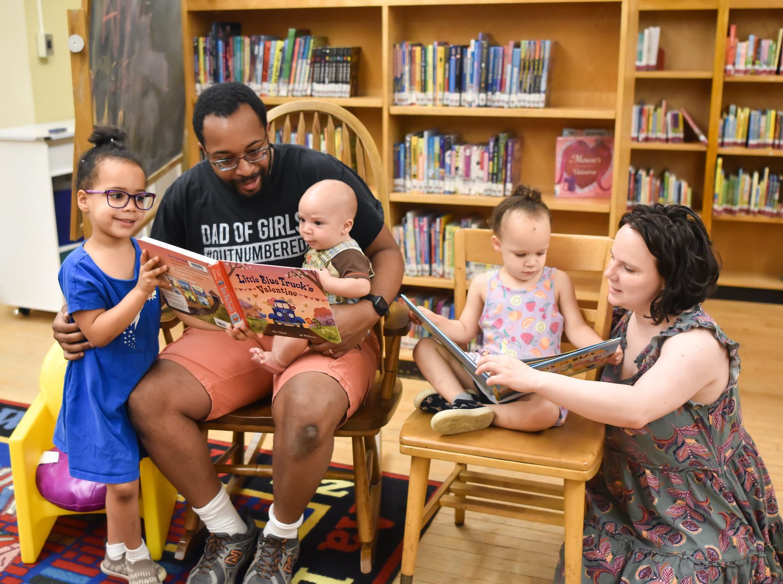 The Lemaire family &mdash; parents Peter and Angelina with children Kiara, Gianna, and Isaiah &mdash; reading picture books together at the library